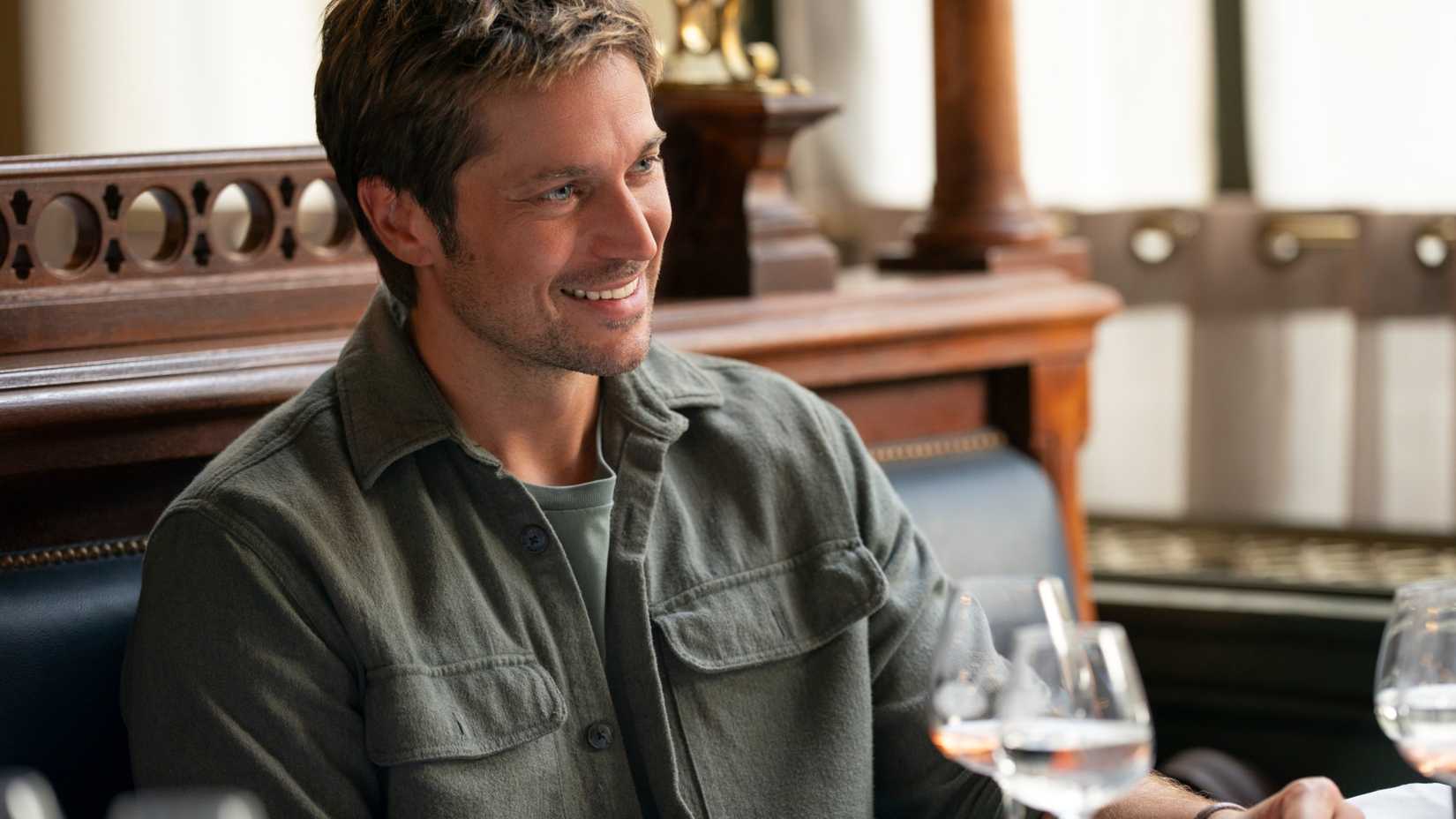 Gabriel Lucas Bravo smiling at a restaurant in Emily in Paris season 5