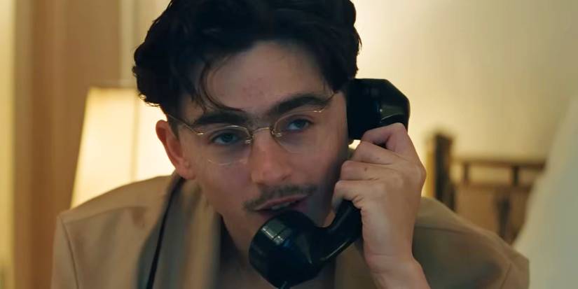 Timothée Chalamet on the phone in a hotel room in Marty Supreme
