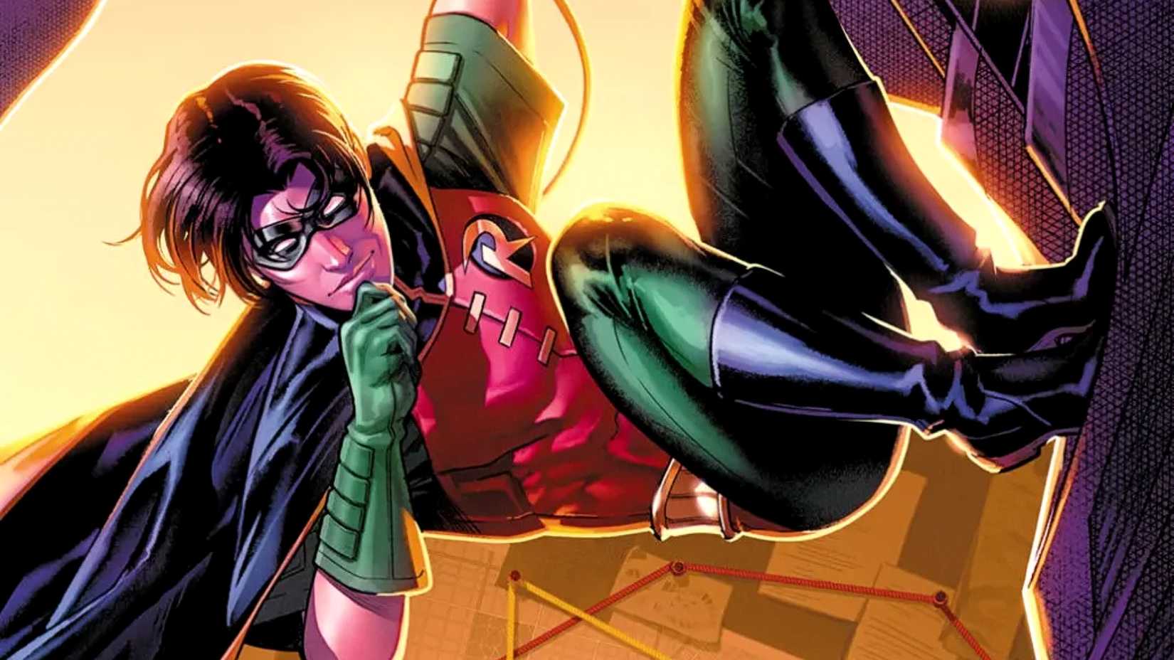 Tim Drake aka Robin rubs his chin while he hangs from a building